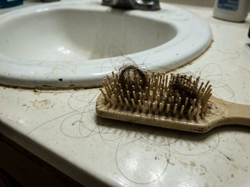 Escova de cabelo com muitos fios presos nas cerdas